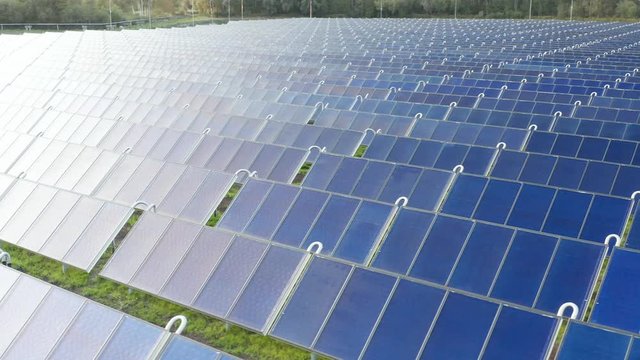 Solar thermal collectors. Solar panels farm field of green renewable energy. in the middle of a forest. Close up drone video of cell panels. Rotates to left. 4k footage