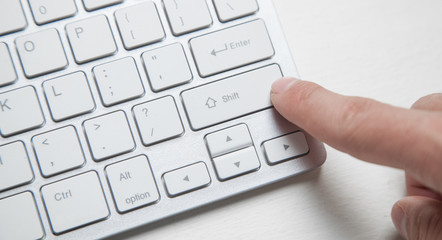 Computer keyboard with finger pressing button.
