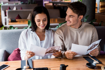 handsome man looking at happy woman smiling holding holding menu