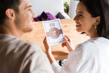 selective focus of woman holding menu and looking at man