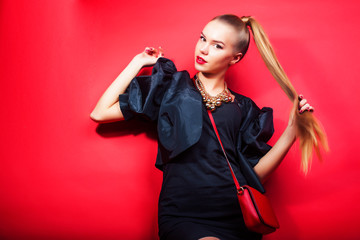 young pretty lady in black suit and small handbag posing on red background, lifestyle people concept