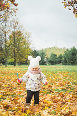 Small girl having fun in autumn day while using bubble wand and blowing bubbles