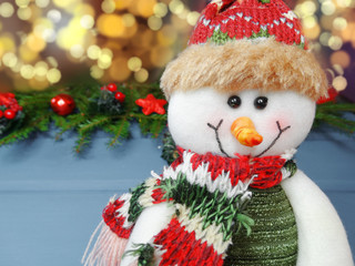 christmas snowman decoration and garland lights on vintage wooden background