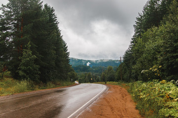 A road in a rainy day. Heavy clouds are above