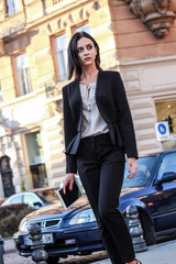Black haired girl.Business woman in black classic suit.White blouse.Fashion style.Working on tablet.Walk