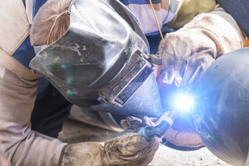 Construction worker welding pipes on a heavy site.