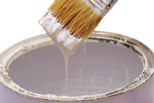 Closeup Of White Paint Dripping From The Brush Into A Tin