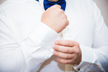 Groom buttons cuffs on his shirt
