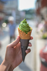 Close up focus of hand holding green tea ice cream gelato in summer.