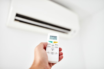 Modern air conditioner unit with a hand holding a remote.
