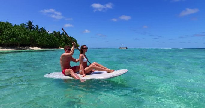 Couple rowing on a surfboard in Thailand