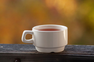 a white Cup stands with tea on the balcony railing