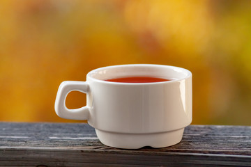 a white Cup stands with tea on the balcony railing