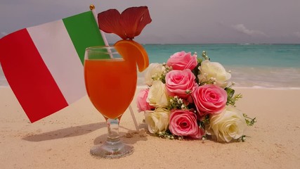 Footage of an Italian flag with a beautiful bouquet and a glass of orange juice next to it on a beach in the Maldives 4K - Powered by Adobe