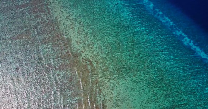 Aerial establishing shot displaying the vivid layers and textures of the sea bottom of the Maldives in 4K