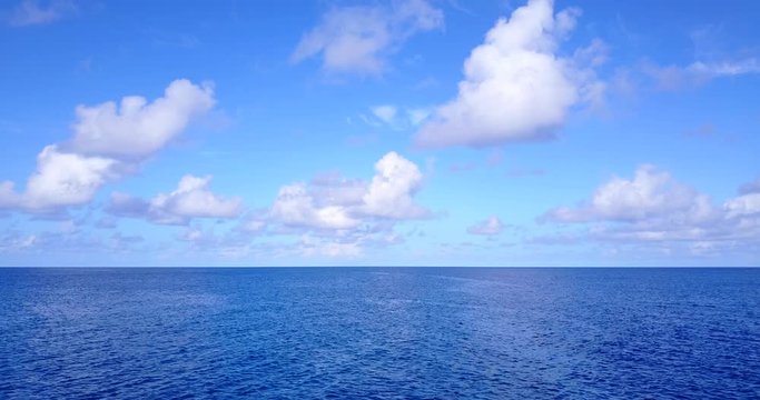 Footage of a drone descending to sea level with some clouds on the distance and a vast sea with nothing in it, Australia 4K