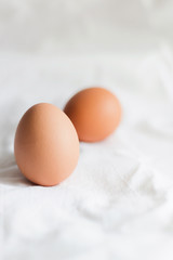 Brown chicken eggs on a light background of cotton fabric, Studio photo, light from the window, selective focus.