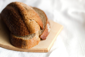 Fresh sliced bread on a wooden Board on a light background of cotton fabric, Studio photo, light from the window, selective focus