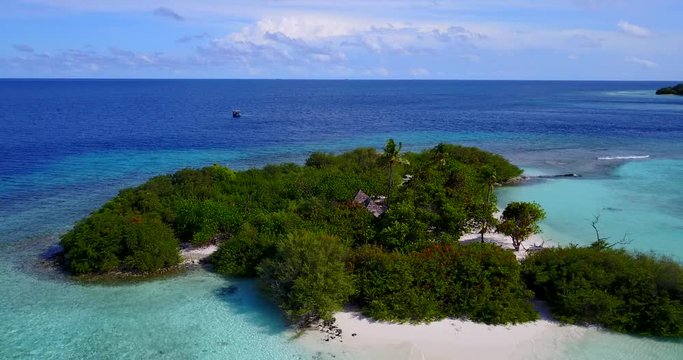 Drone flying above an exotic small island with green vegetation and a hut in the middle, with sandy white beaches and some clouds on the distance in Thailand 4K
