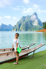Fototapeta na wymiar Asian woman standing on wooden boat with mountain and lake