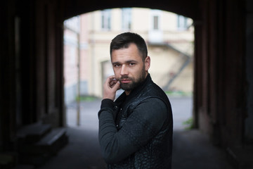 Pensive bearded young man outdoors in the afternoon in the city.