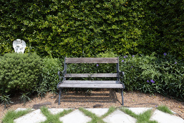 single wooden bench chair with stone grid walkway pavement and pebble or gravel in exterior garden.