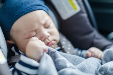 Cute sleeping baby in child car seat going for a family road trip