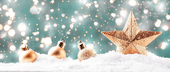 Christmas background with golden star. New Year's decor. Christmas balls in smowdrifts and golden bokeh lights