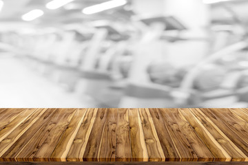 Empty wooden board space platform with blur fitness gym equipment background