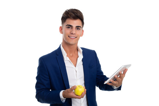 young smiling businessman carrying a white tablet mobile and an apple. He is wearing a blue jacket suit and a white shirt. He is in a photo studio.