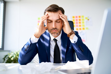 Portrait of businessman suffering from headache in office