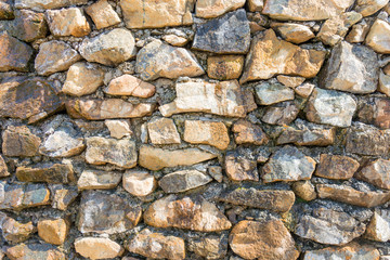 Stone wall with cement. Decorative uneven cracked stone is a real stone wall.