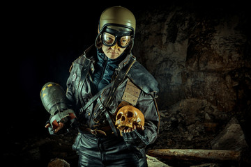 Soldier woman with the bomb in one hand and skull in another on the ruined background.
