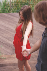 Vertical photo. A young couple a guy and a girl are walking in the park and holding hands. Love story. Pregnancy