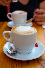 White cup with cappucino coffee with whipped hot milk