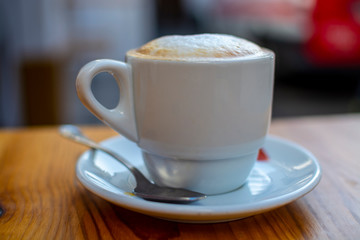 White cup with cappucino coffee with whipped hot milk