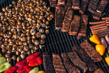 Assorted delicious grilled meat with vegetable on a barbecue with t-bone steak and mushrooms. large rotary grill, field kitchen, food court
