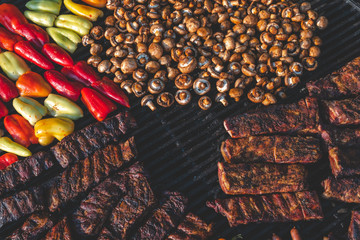 Assorted delicious grilled meat with vegetable on a barbecue with t-bone steak and mushrooms. large rotary grill, field kitchen, food court