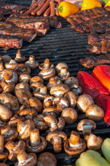 Assorted delicious grilled meat with vegetable on a barbecue with t-bone steak and mushrooms. large rotary grill, field kitchen, food court, vertical photo
