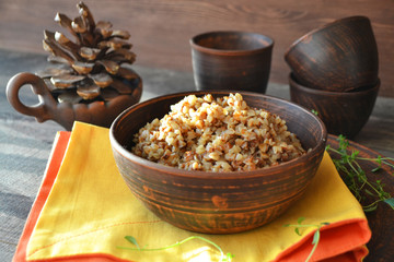 Bowl of hot buckwheat porridge, bright napkin on the village table.
