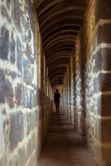 Obraz premium Une silhouette marchant dans un couloir étroit. Une personne marchant dans un couloir de château fort.