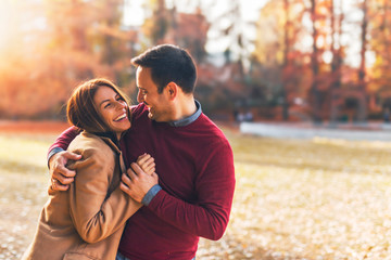 Happy couple at public park in autumn - obrazy, fototapety, plakaty