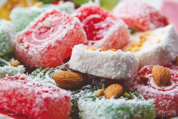 Closeup of sweets Turkish delight. Red Turkish delight of red, white and green with almond nuts. Photography of desserts.