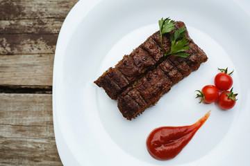 Food in the restaurant. Grilled pork with cherry tomatoes. White plate on a wooden bottom.