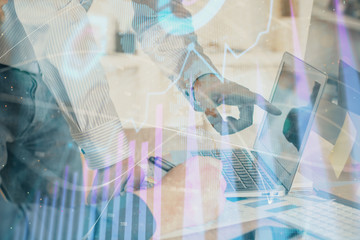 Double exposure of chart with businessman typing on computer in office on background. Concept of hard work.