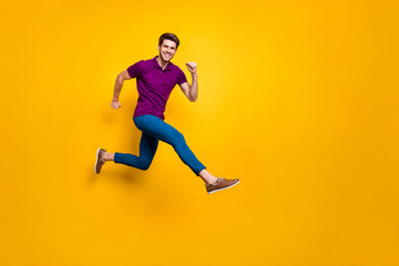 Full length body size phoo of cheerful brown haired attractive man wearing blue pants trousers purple t-shirt footwear aspiring jumping running isolated over yellow vivid color background
