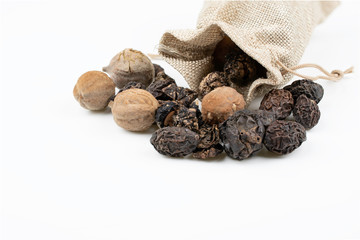 triphala ayurvedic medicinal plant comprise of  organic chebulic myrobalan fruit, organic amla fruit, and organic belleric myrobalan fruit in cloth sack on white background with copy space