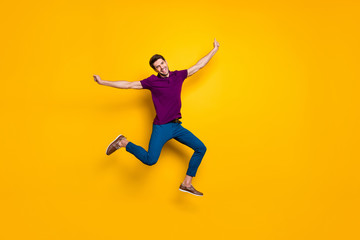 Full length body size photo of cheerful ecstatic free man wearing blue pants trousers aspiring jumping running towards future isolated over yellow vivid color background
