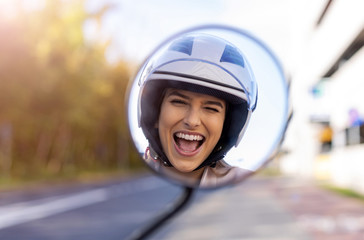 Reflection of beautiful young woman in motor scooter mirror 