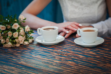 Pair of gold wedding rings and two cups of coffee